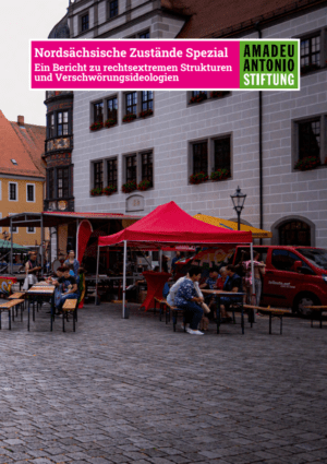 Auf dem Bild ist ein Platz zu sehen, auf dem Pavillons und eine Bühne aufgebaut sind. Dabei stehen Biertisch Garnituren und auf den Bänken sitzen Menschen und unterhalten sich. Bei einem Pavillon und an der Bühne hängen Regenbogenflaggen. Oben im Bild ist das Logo der "Amadeu Antonio Stiftung" zu sehen und daneben steht der Titel der Dokumentation "Nordsächsische Zustände Spezial. Ein Bericht zu rechtsextremen Strukturen und Verschwörungsideologien."